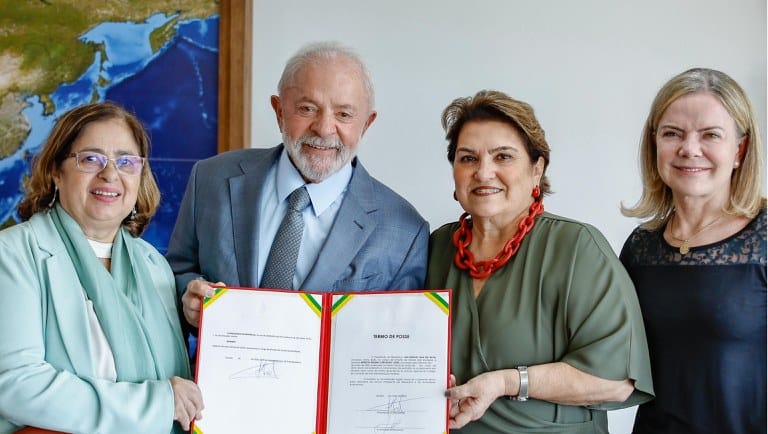 três mulheres brancas e um homem branco segurando um documento