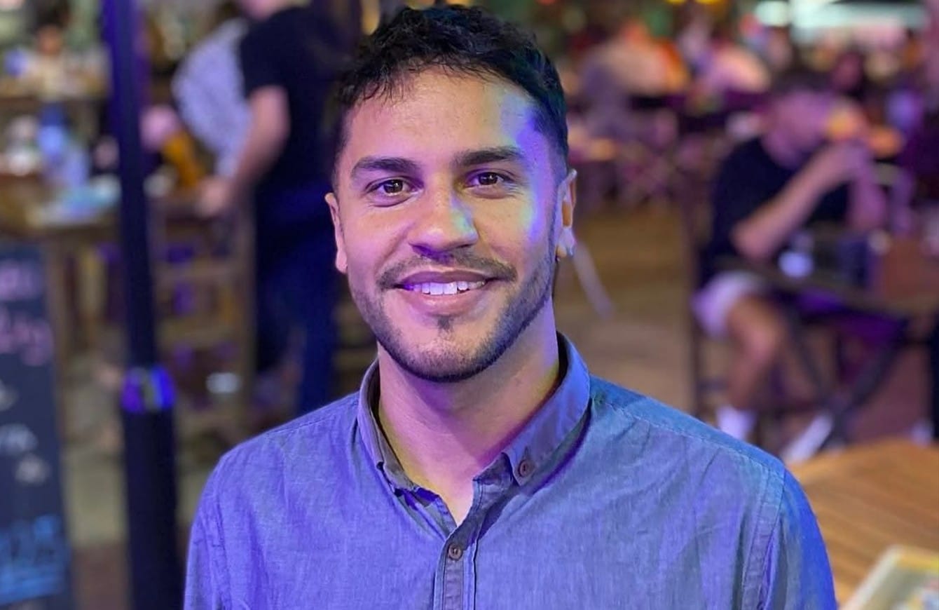 homem pardo de camisa azul sorrindo