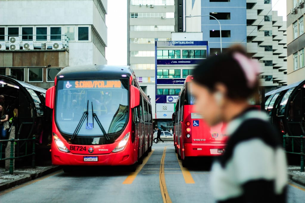 ônibus laranjado e mulher desfocada em primeiro plano