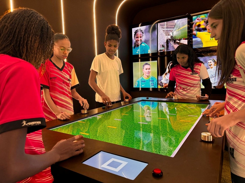 meninas olhando mesa interativa de futebol