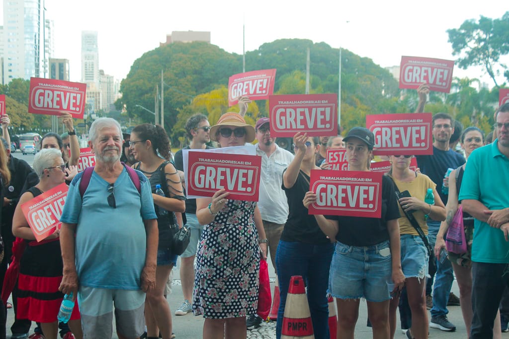 pessoas segurando placas com a palavra "greve"