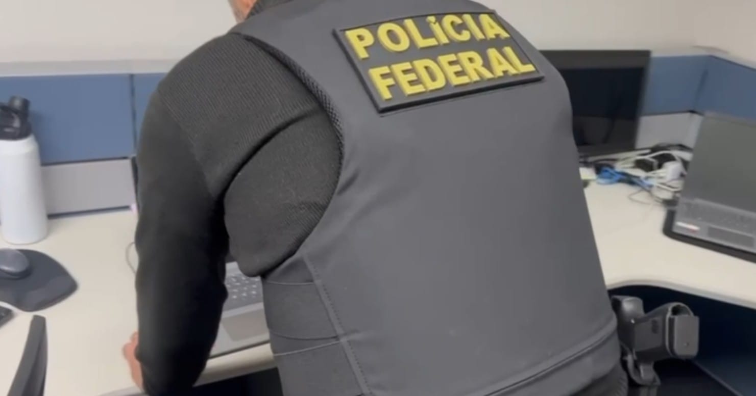 homem branco de costas com colete escrito polícia federal