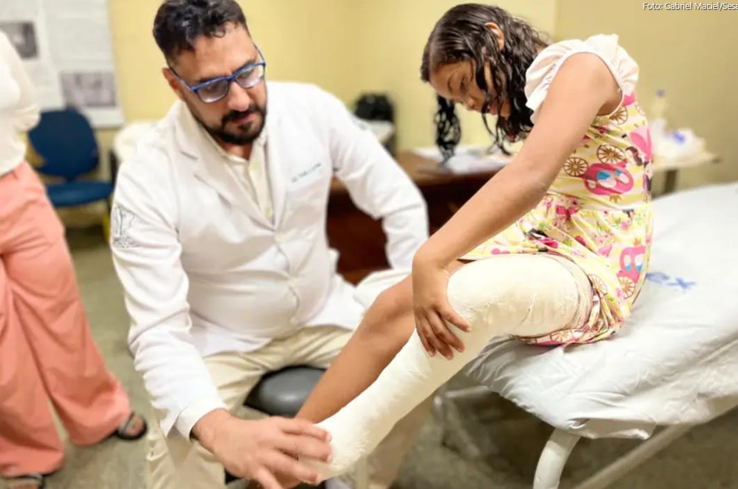 homem branco médico atendendo menina branca com perna quebrada