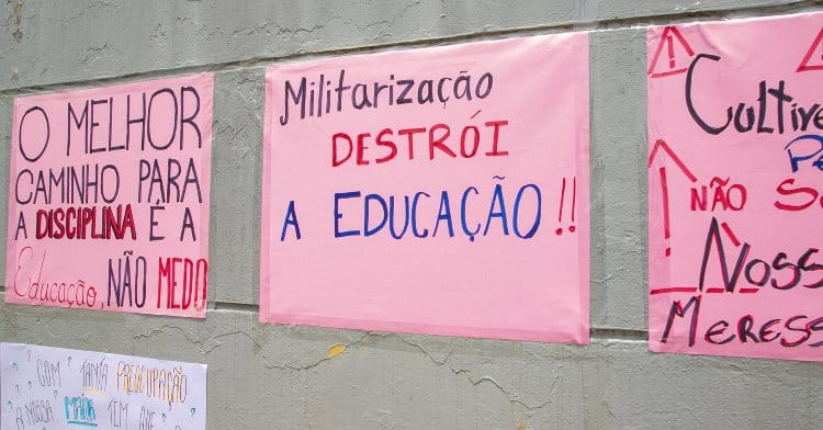 cartaz rosa escrito 'militarização destrói a educação'