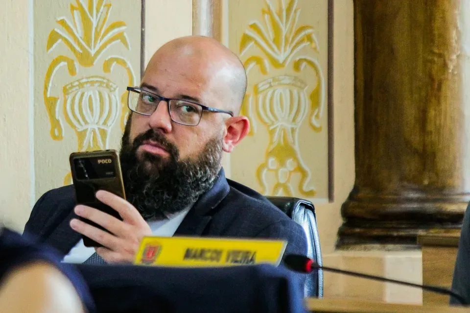homem branco de óculos mexendo no celular