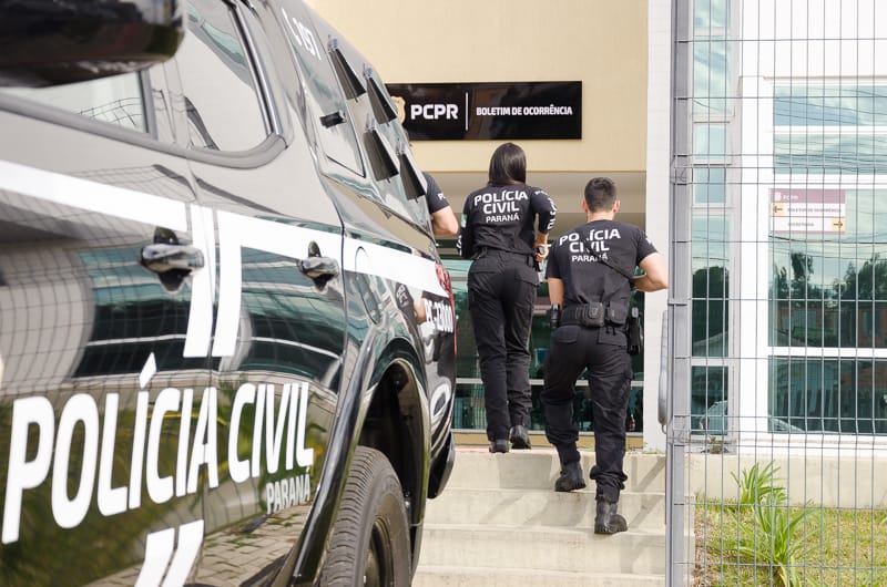 viatura em primeiro plano e policiais civis no segundo plano