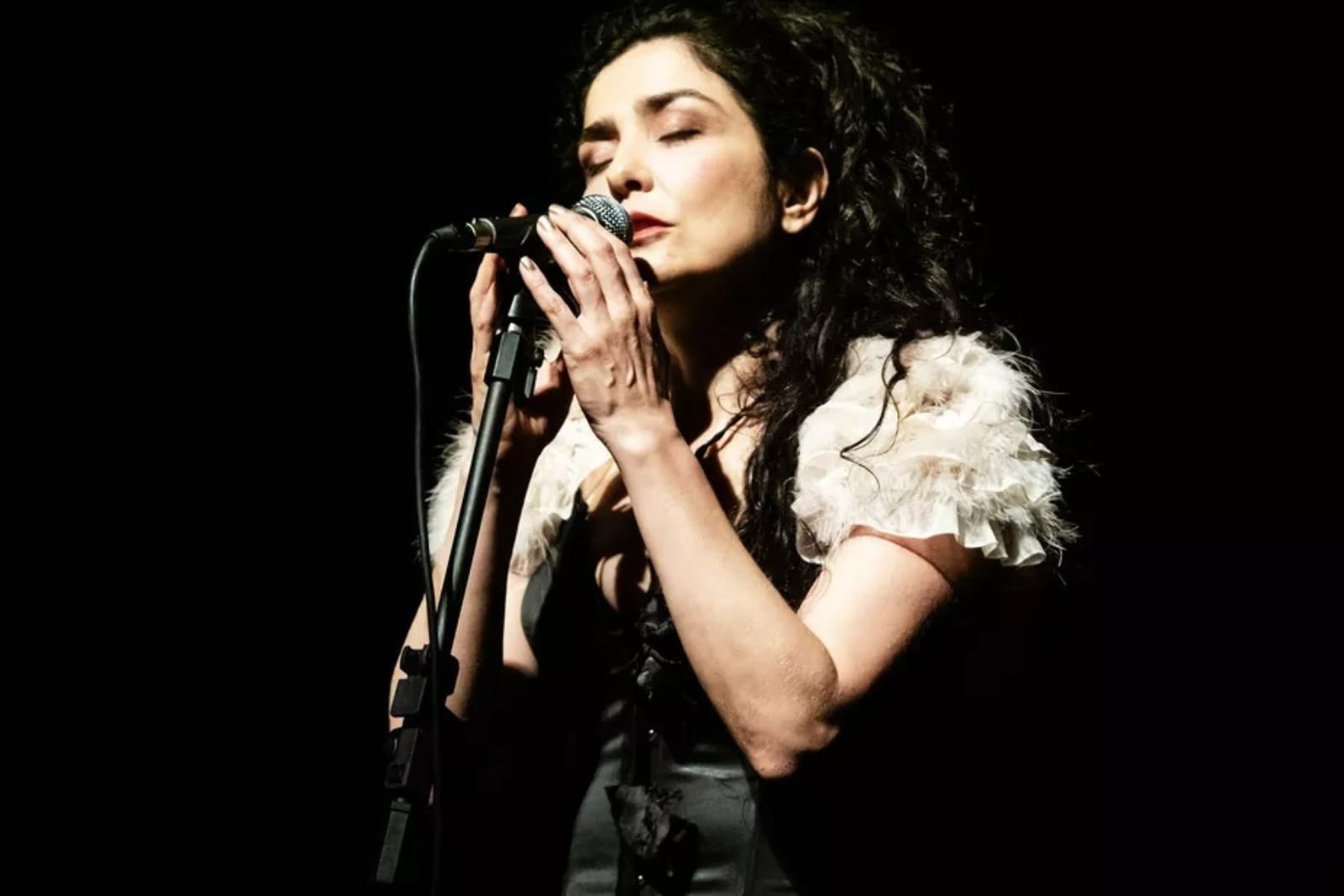 Letícia Sabatella canta ao microfone em show com o músico Fabiano O Tiziu