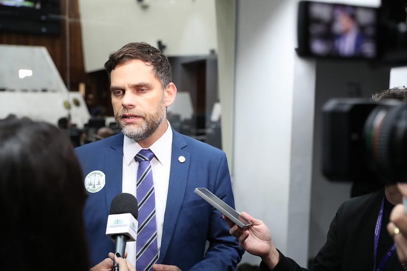 homem branco de gravata dando entrevista