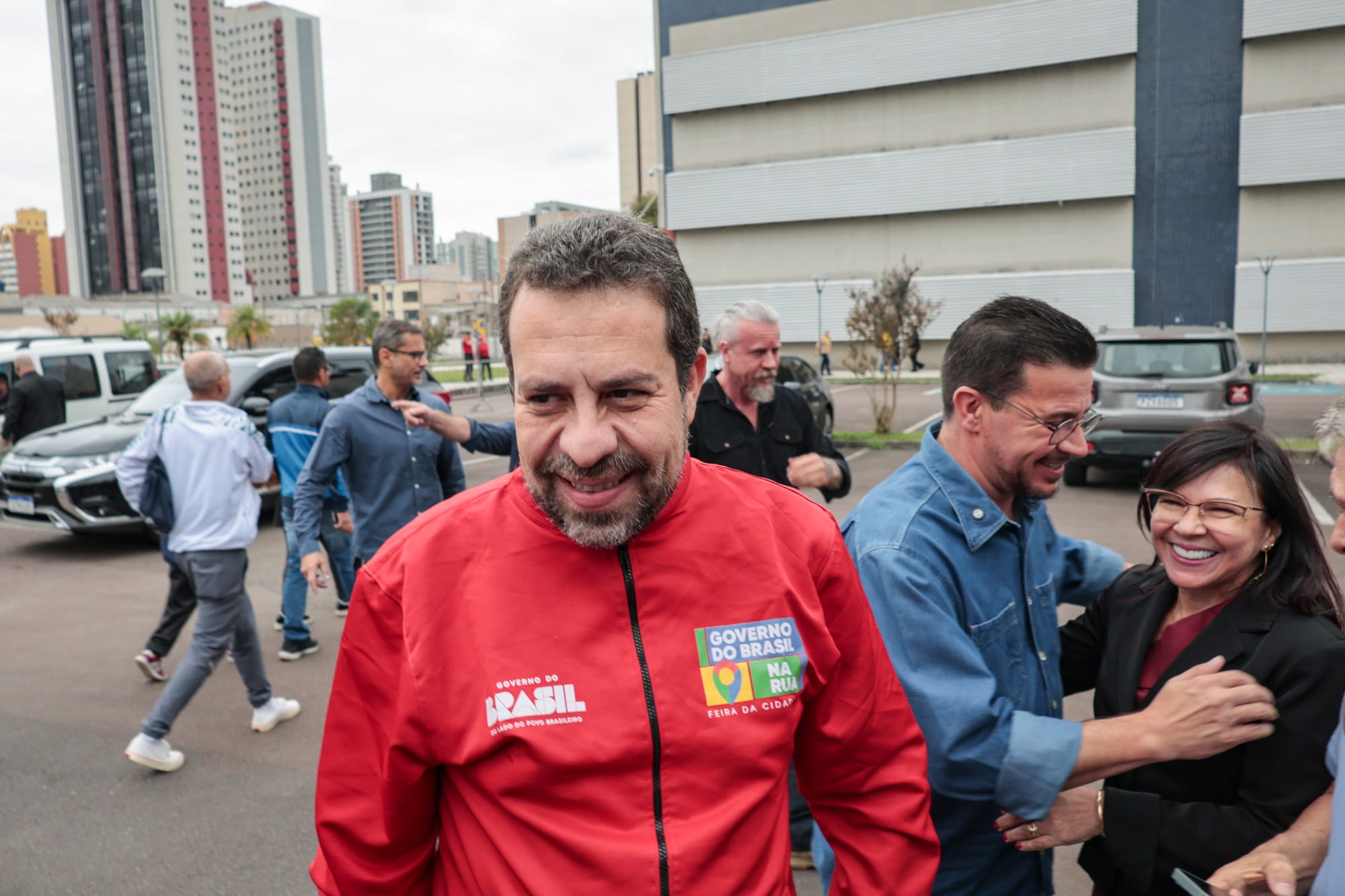 homem branco sorrindo com blusa vermelha